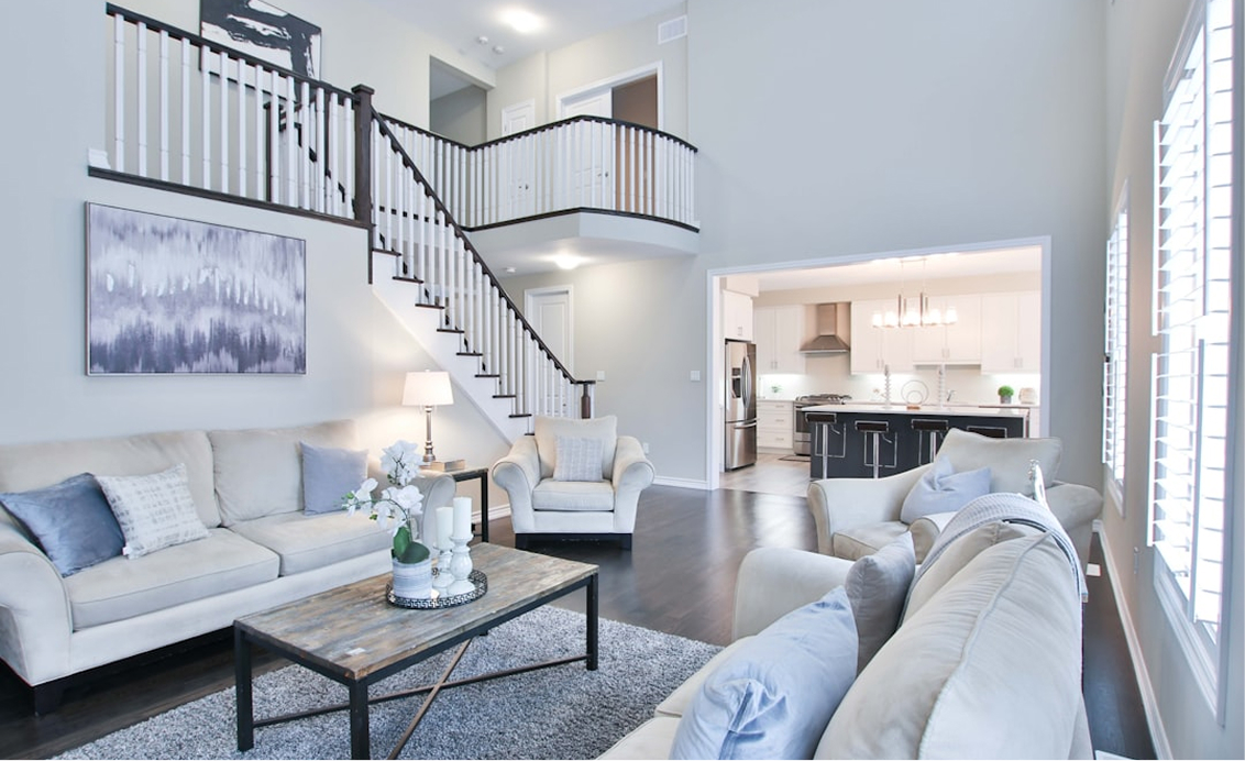 A clean living room with a staircase in the background, as well as a kitchen area, professionally cleaned by Professional Edge Cleaning in Fredericksburg, VA.
