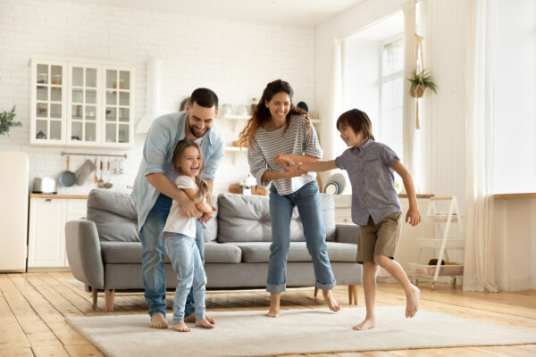 Happy family playing funny game having fun together with little son and daughter in modern living room.
