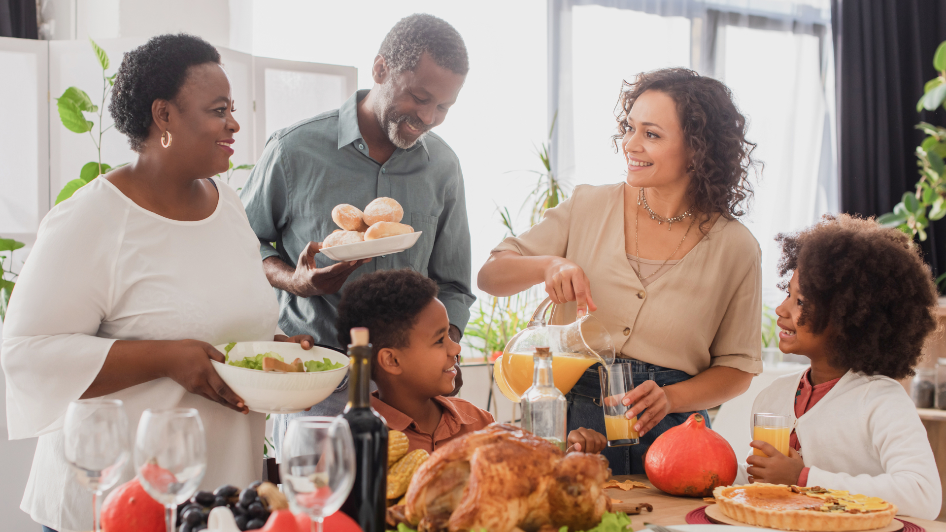 A family enjoying Thanksgiving dinner together in a clean, bright dining room with fresh food and natural light, representing the comfort and peace of mind that comes from using a professional deep cleaning service before the holidays.
